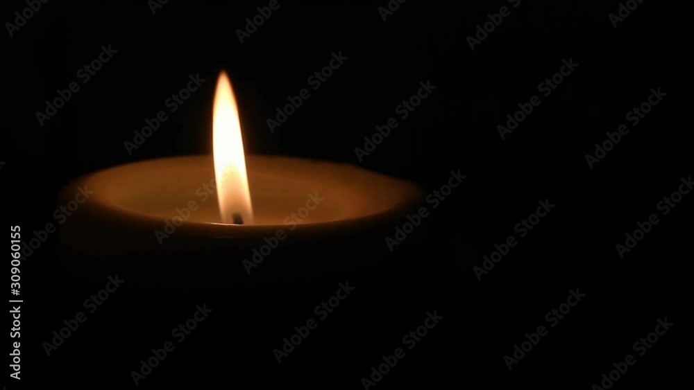 A single pillar candle burning with a flickering flame lights the darkness - great copy space in a seamlessly looping video A single pillar candle burning with a flickering flame lights the darkness - great copy space in a seamlessly looping video
