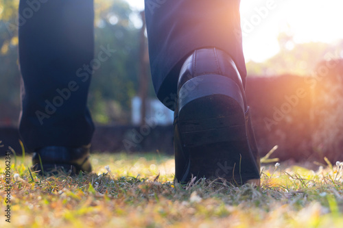 Close up business man walking on grass in public park. He is wearing black shoe and step up in to grass in a yard.good health,going, objective,Photo active and goal concept idea.