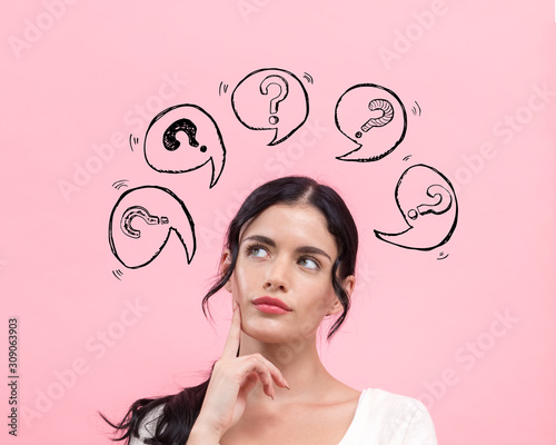 Question marks with speech bubbles with young woman in thoughtful pose