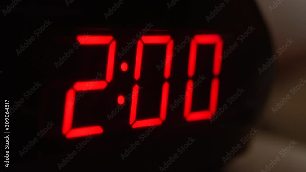 Close-up of black digital clock screen showing 2.00. Blinking red digital numbers on black background. Modern timer system and neon light, electric alarm device