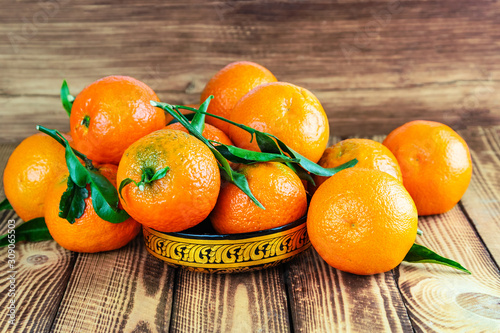 Fresh organic tangerines in beautiful gold bowl on old wooden background