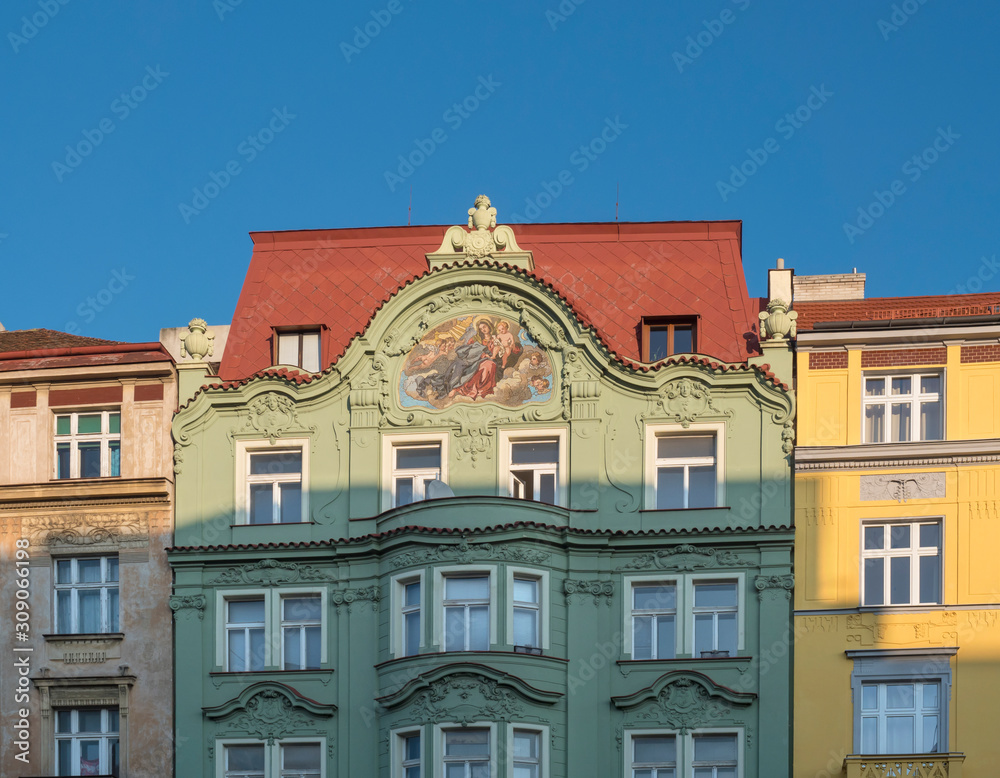Obraz premium Beautiful green, yellow and pink ancient historical residential house facades with fresco at Letna, Prague, Czech Republic. Blue sky background