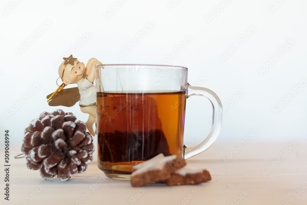 Cup of tea decorated with sweet angel, pine cone and cookies on white wooden table Cup of tea decorated with sweet angel, pine cone and cookies on white wooden table