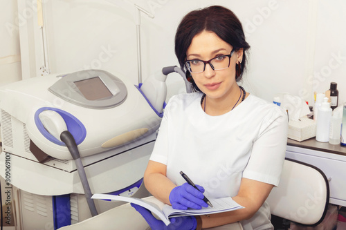 Friendly female doctor cosmetologist working with documents in modern cosmetic office