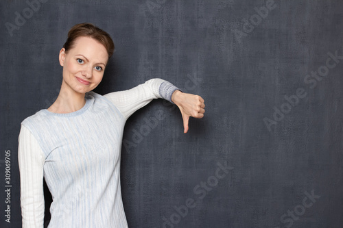 Portrait of happy girl showing thumb down in dislike gesture