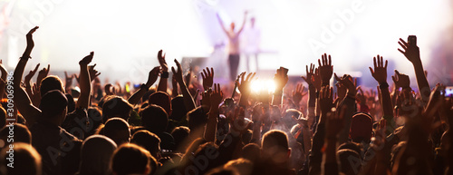 crowd with raised hands at concert festival banner