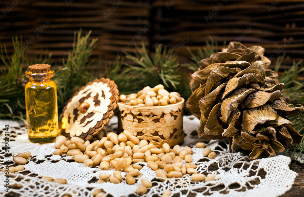 Cedar nuts, cones and oil with branch on a wicker background.