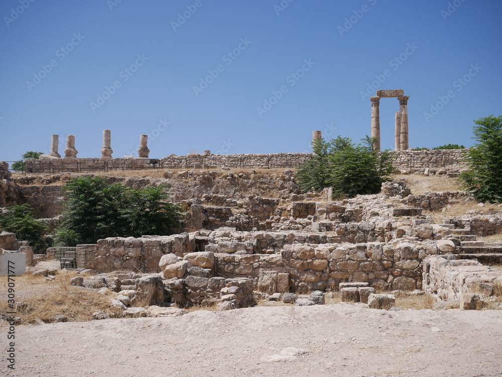 Roman ruins of the citadel of Amman, capitol of Jordan, remains of a city build from stone and tall pillars on a brown hill in the middle of a city