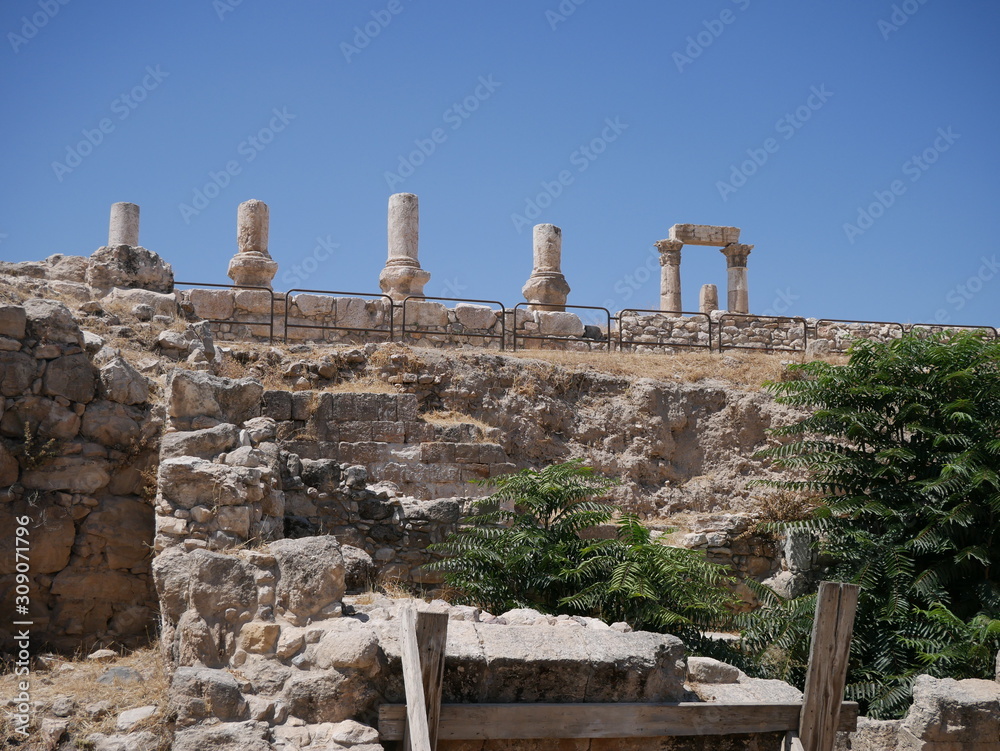 Roman ruins of the citadel of Amman, capitol of Jordan, remains of a city build from stone and tall pillars on a brown hill in the middle of a city