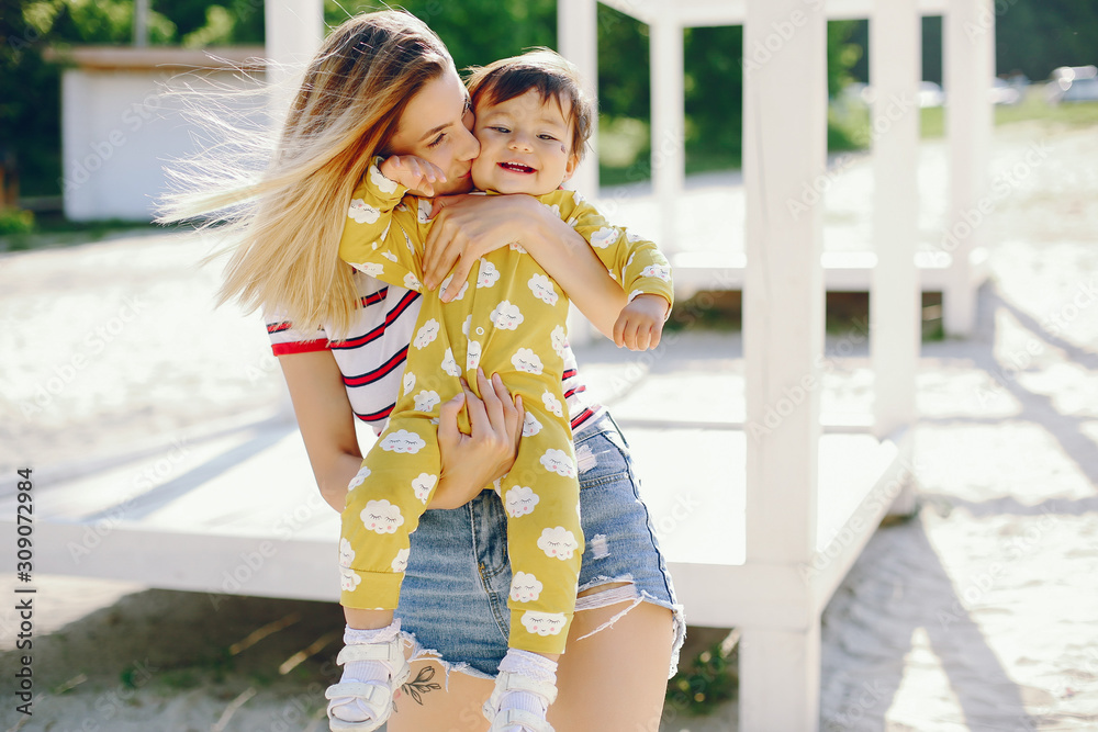 Fototapeta premium Pretty mother with little daughter. Family in a park. Little girl in a yellow clothes