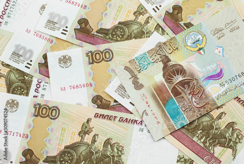 A colorful quarter dinar bank note from Kuwait close up in macro with Russian one hundred ruble bills