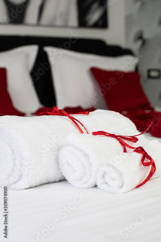 Freshly laundered fluffy towels on bed in hotel room. Red decorations.
