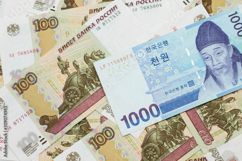A blue South Korean one thousand won bank note close up in macro on a background of Russian one hundred ruble bank notes