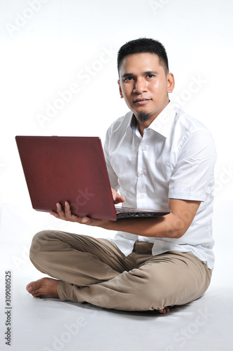 Young Asian business man or Young Asian entrepreneur sit on the white floor holding laptop. Excited of young Asian freelancer.