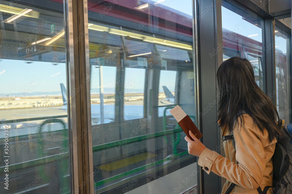 passport and boarding pass in hand of woman passenger awaiting for transit train from terminal to another terminal, airport transit in terminal, transfer in airport terminal by train services