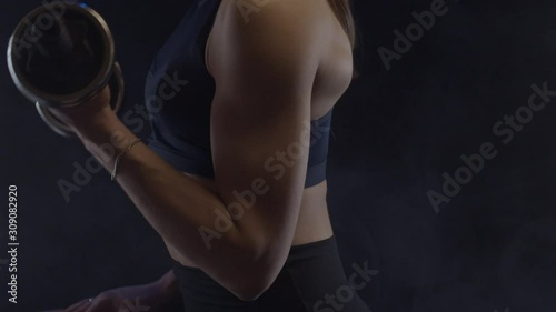 Fit woman doing biceps curls with dumbbells, close up, shot in slow motion