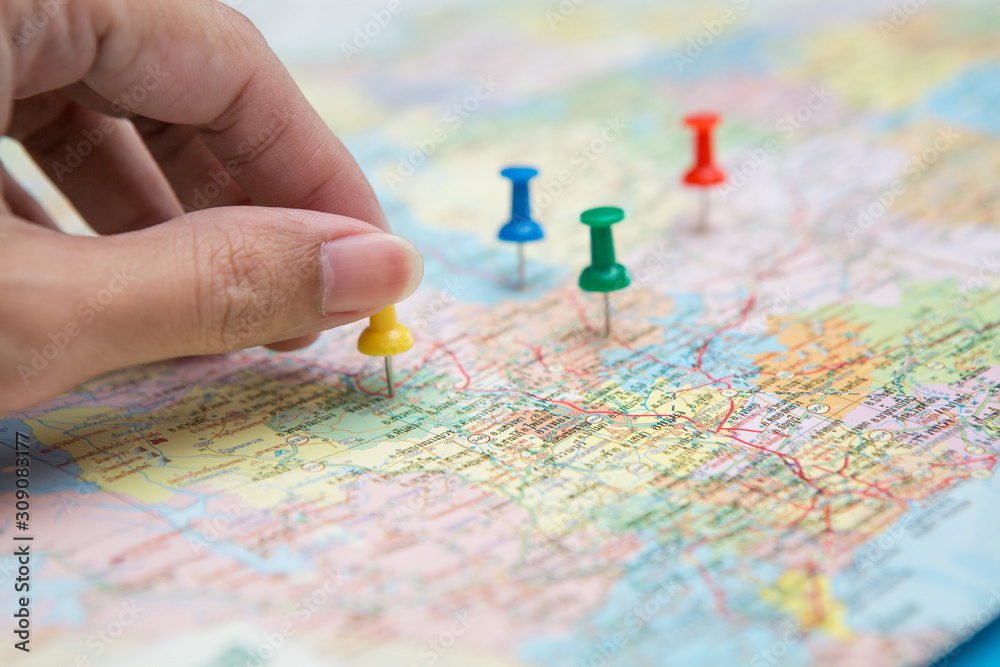 Selective focus of hand holding a pin on map background Selective focus of hand holding a pin on map background