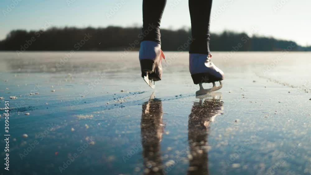 Young woman ice skating on a frozen lake on a freezing winter day. Legs ...