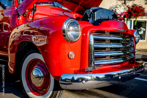 Bright red vintage retro truck with an open hood standing at an exhibition on a street of a provincial town