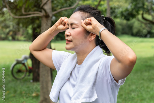 In the morning.Senior woman Asian headache during exercise at the park.