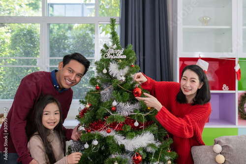 Asian happy family, father, mother, daughter help to prepare and gift or decorate Christmas tree in living room that decorated for christmas festival holiday concept © FrameAngel