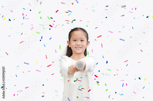 Happy little Asian child girl shooting party popper confetti over white background.