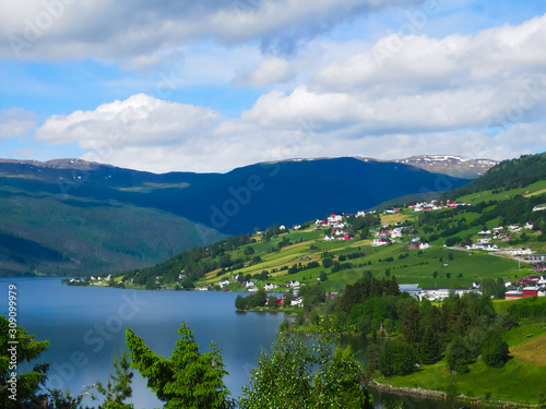 A beautiful Norwegian mountain landscape with fjord and farms in spring with blue sky and clouds. © scandamerican