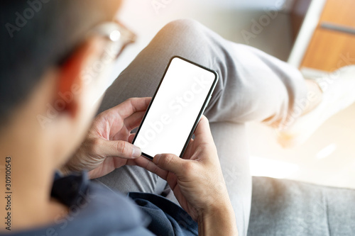 Mockup image blank white screen cell phone.men hand holding texting using mobile on sofa at home office.background empty space for advertise text.people contact marketing business and technology 