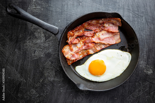 Fried eggs and bacon for breakfast on a frying pan, top view, copyspace