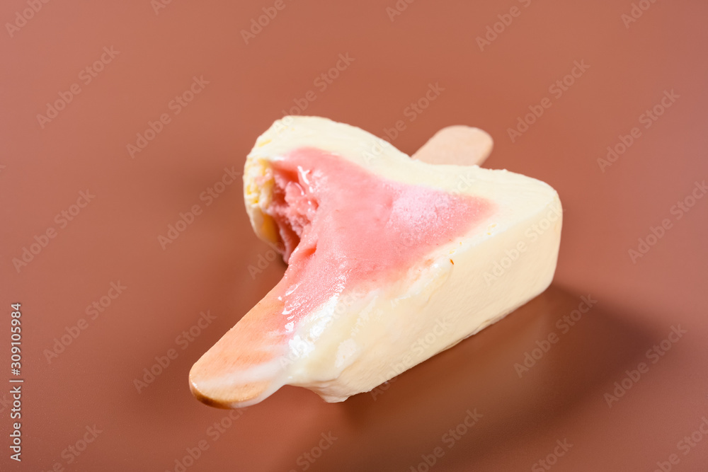 side view half eaten strawberry flavor popsicle on a brown background side view half eaten strawberry flavor popsicle on a brown background