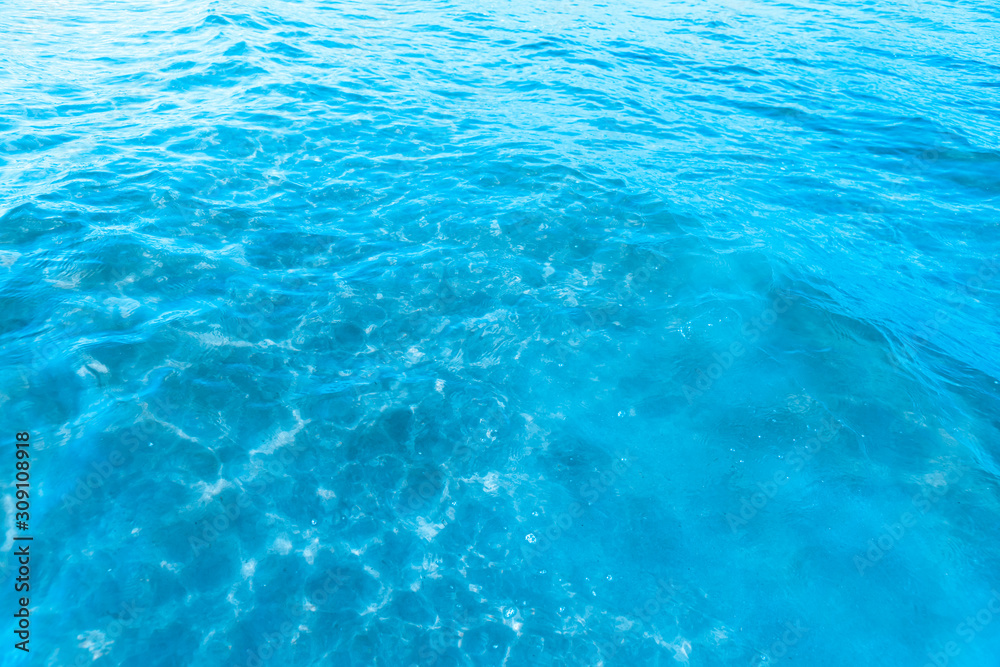Blue transparent sea water near the beach texture background. clear water surface with slight waves and glare on a sunny day. sea ​​vacation