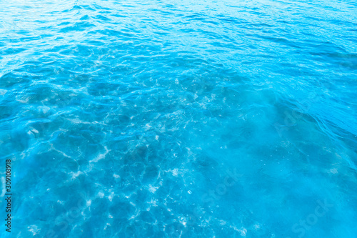 Blue transparent sea water near the beach texture background. clear water surface with slight waves and glare on a sunny day. sea ​​vacation