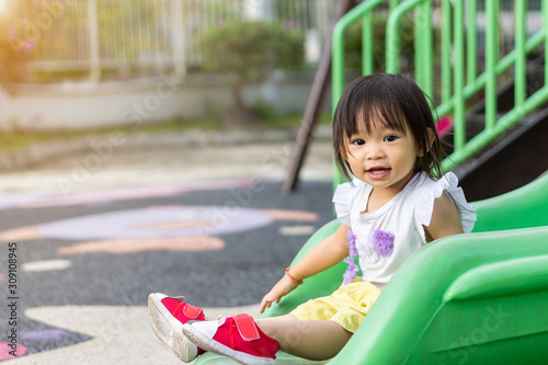 Portrait image of 1-2 yeas old baby. Happy Asian child girl smiling and laughing. She playing with slider bar toy at the playground. Learning and active of kids concept. photo