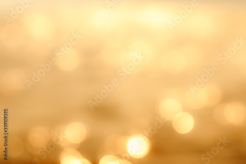 Delicate golden texture bokeh background. blurry yellow bokeh glare on the water during sunset and dawn