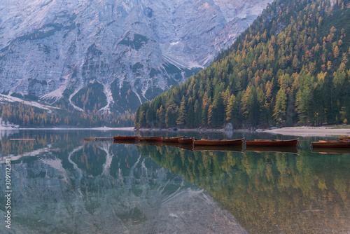 Natural landscapes of the lake Braies (Lago di Braies) with morning fog and reflection of the mountain peak in Dolomites, Italy