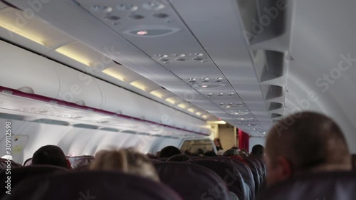 Passengers of economy class sit calmly in cabin of airplane. People took teir seats, waiting for arrival. photo