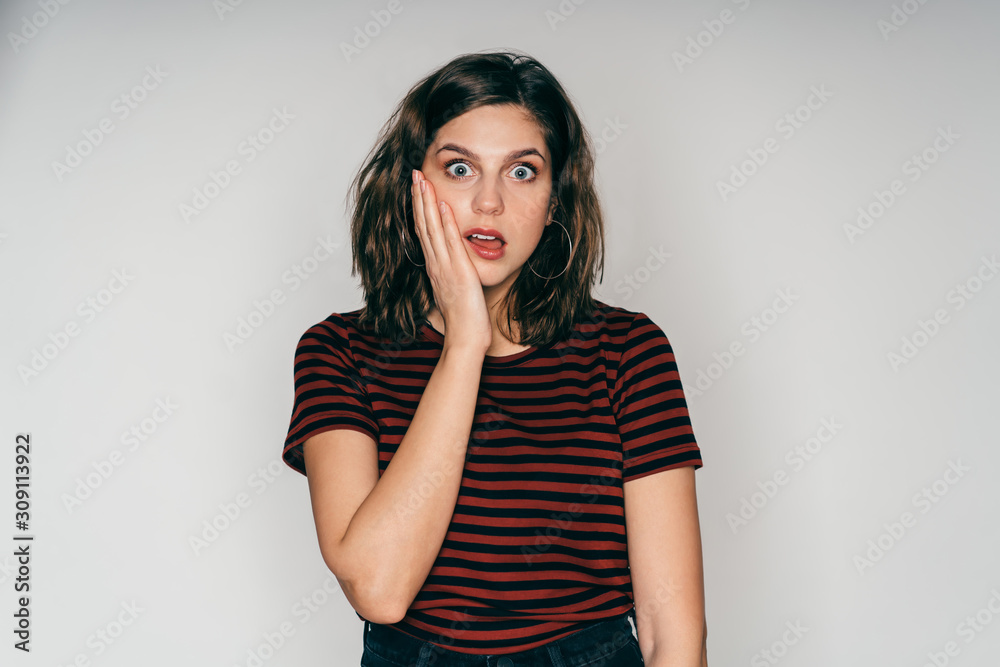 Amazed adult pretty female touching cheek in studio Amazed adult pretty female touching cheek in studio