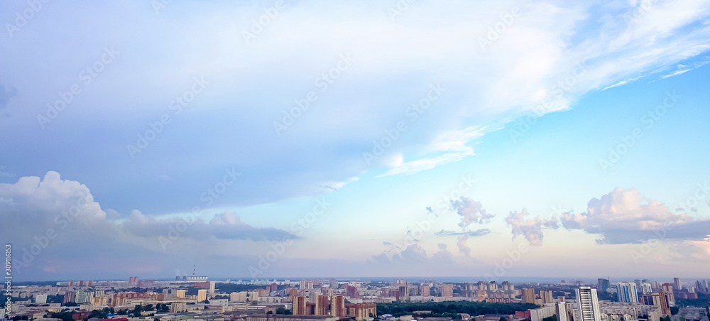 Aerial view of the landscape in a big city with high houses and skyscrapers in the center of Novosibirsk under a beautiful blue sky with clouds on a summer cloudy day.
