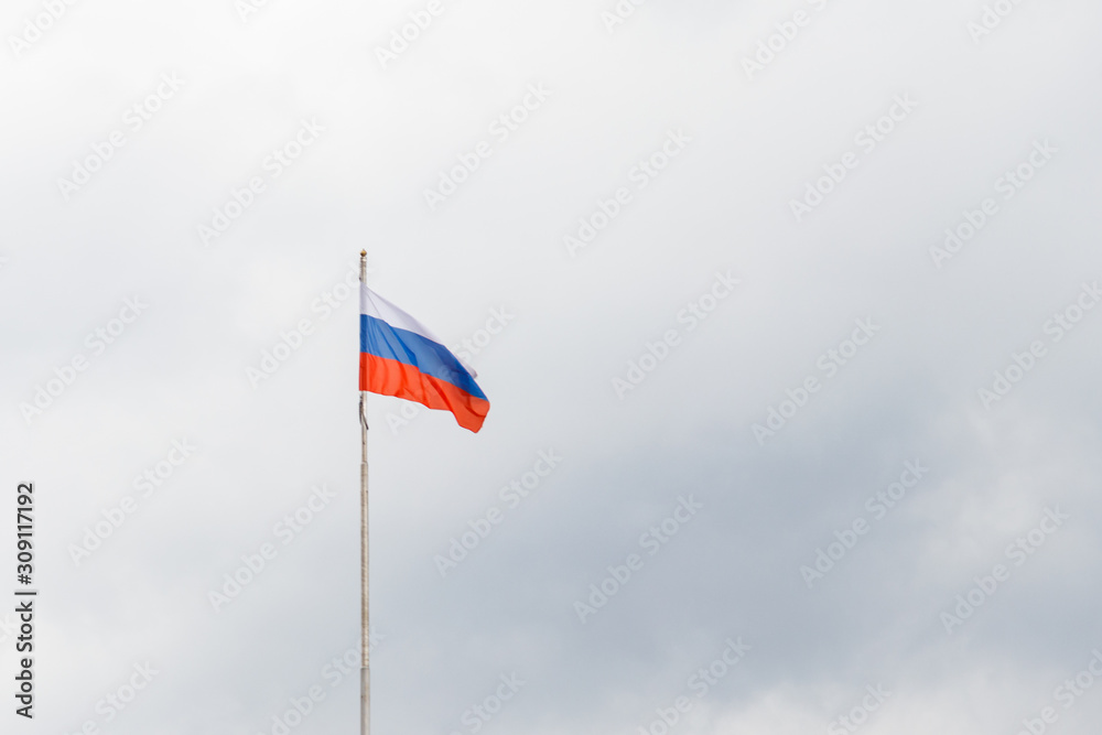 Waving flag of Russia against gloomy cloudy sky