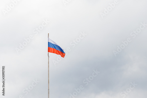 Waving flag of Russia against gloomy cloudy sky