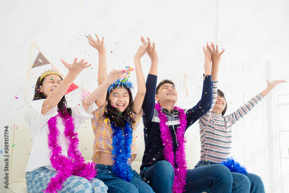 Group of Happy Asian teenager Raise Hands Up and Enjoy Throwing Colorful Confetti with Friends in Party