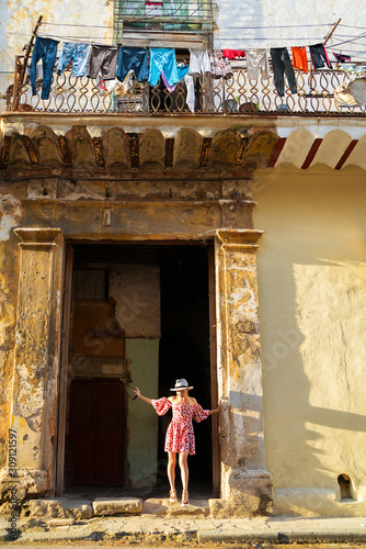 Young woman in a colored dress leaves a dilapidated house © Denis Aglichev