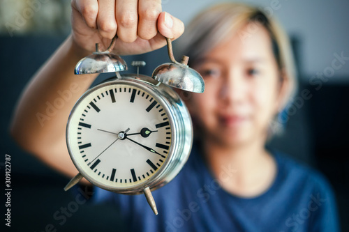 A Women hold clock in hand.