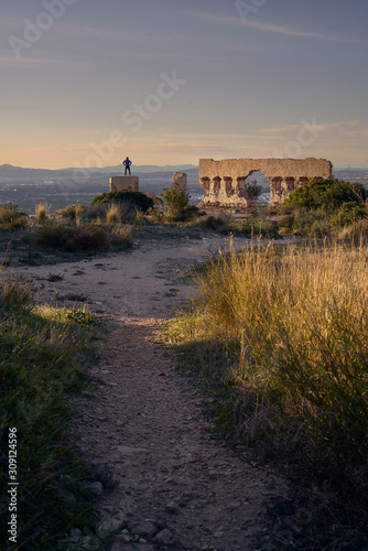 person contemplates the landscape from the top of a ruined tower photo