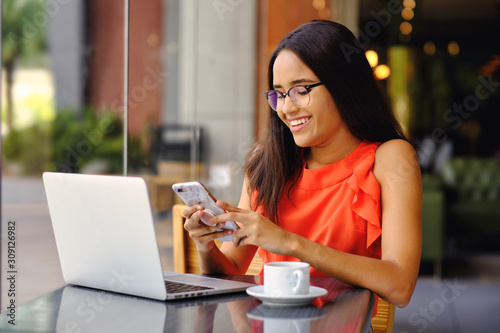 Young latinamerican girl chatting in cafe with a cellphone