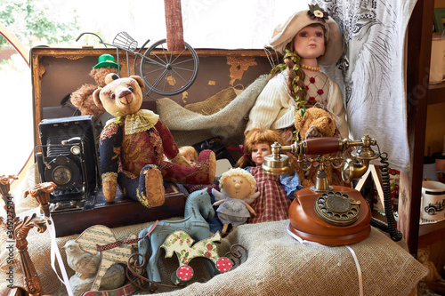 Fototapet Suitcase with toys and dolls (Teddy bear) and a vintage telephone