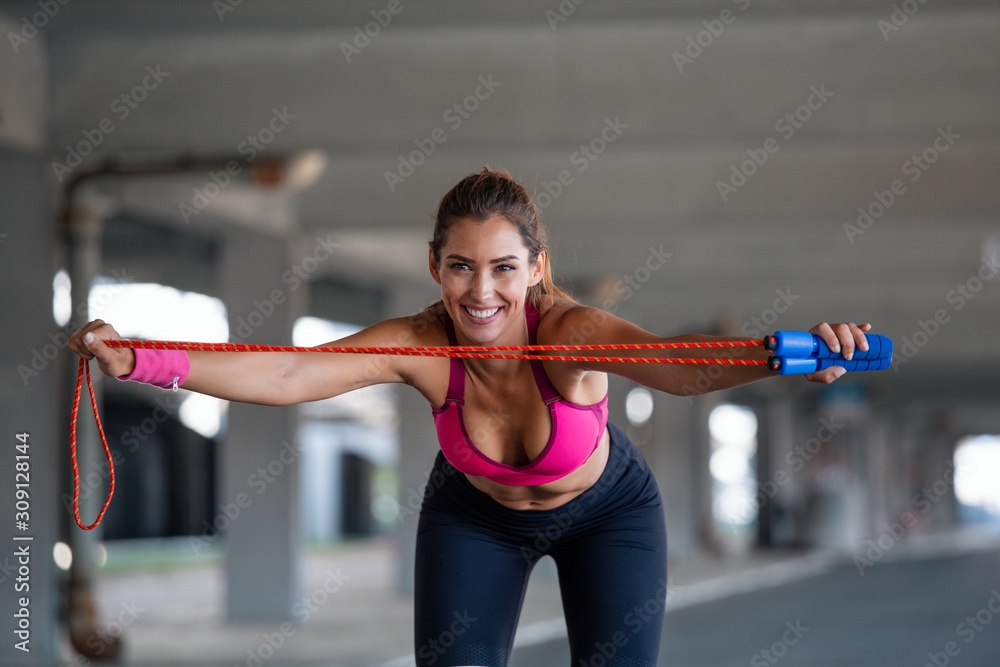Athletic Beautiful Woman Exercises with Jump / Skipping Rope. She's Covered in Sweat from Her Intense Fitness Training. - obrazy, fototapety, plakaty 