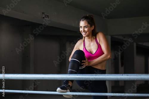 fitness, sport, exercising and lifestyle concept - close up of couple stretching leg on stands of stadium. Beautiful young girl stretching her hamstrings. Photo of sporty girl doing exercising.