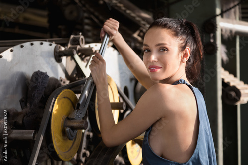 Fotografia Beautiful girl repairs the spinning machine with an adjustable wrench