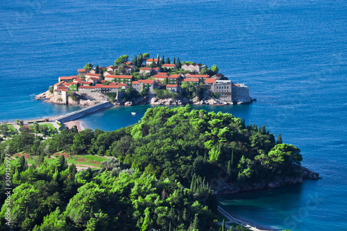 island and green peninsula. houses with a tiled roof and green trees by the blue sea. happiness in relaxation in warm countries. Sveti Stefan, Montenegro.